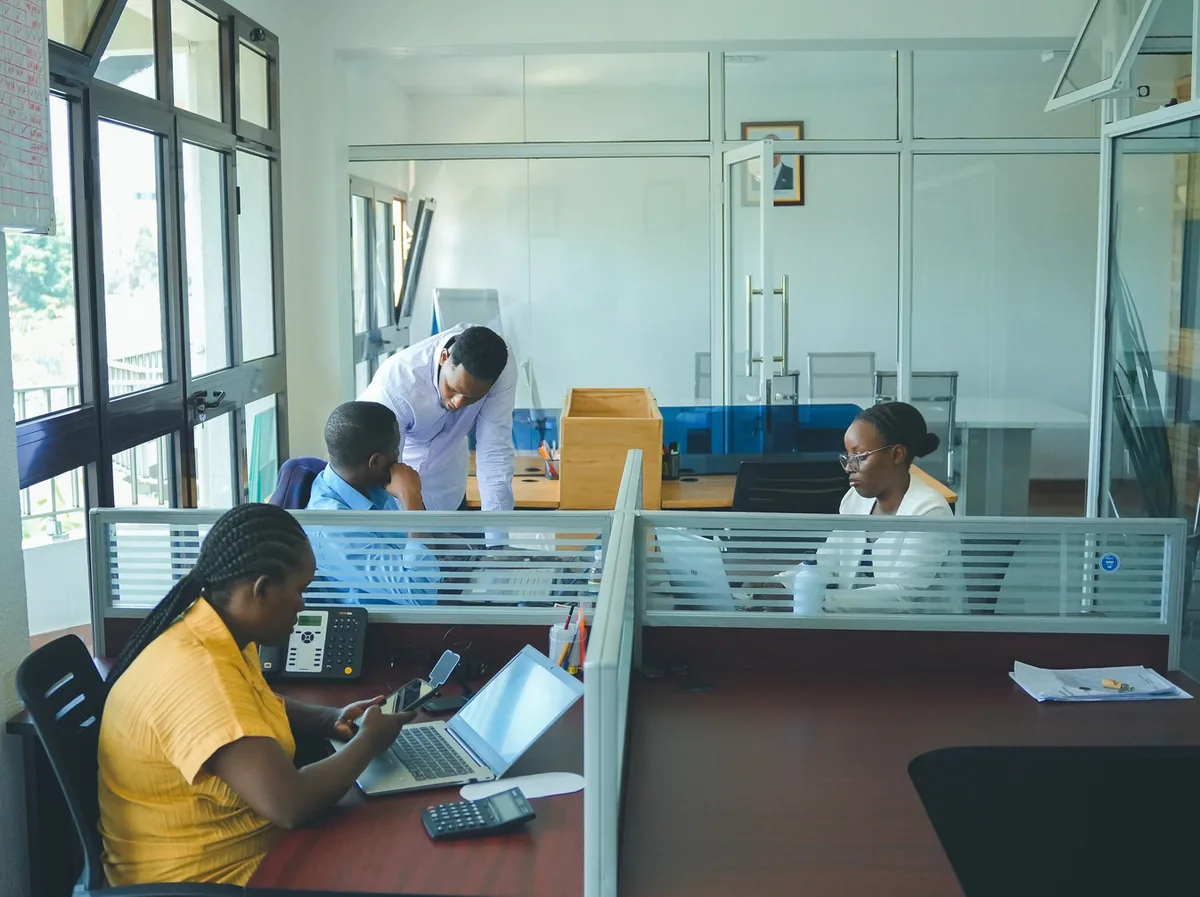 Staff working at desks in an open-plan office with glass partitions